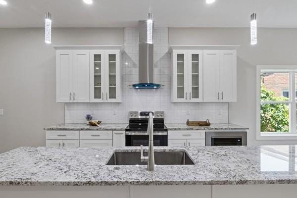 kitchen featuring pendant lighting, wall chimney range hood, and stainless steel electric stove