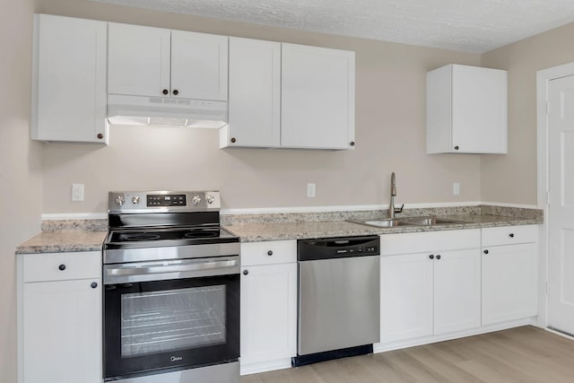 kitchen featuring sink, a textured ceiling, light wood-type flooring, stainless steel appliances, and white cabinets