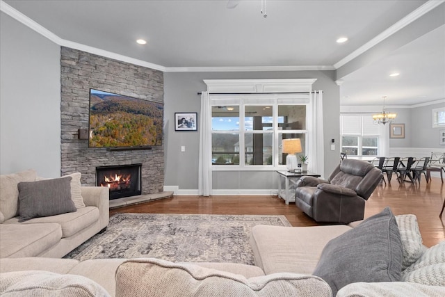 living room featuring an inviting chandelier, a stone fireplace, wood-type flooring, and ornamental molding