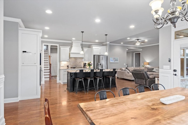 dining room featuring crown molding, ceiling fan with notable chandelier, and wood-type flooring