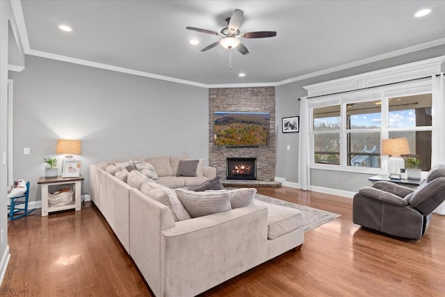 living room with ceiling fan, ornamental molding, dark hardwood / wood-style flooring, and a stone fireplace