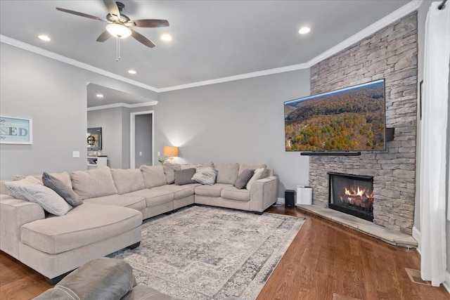 living room with ceiling fan, a fireplace, ornamental molding, and dark hardwood / wood-style flooring