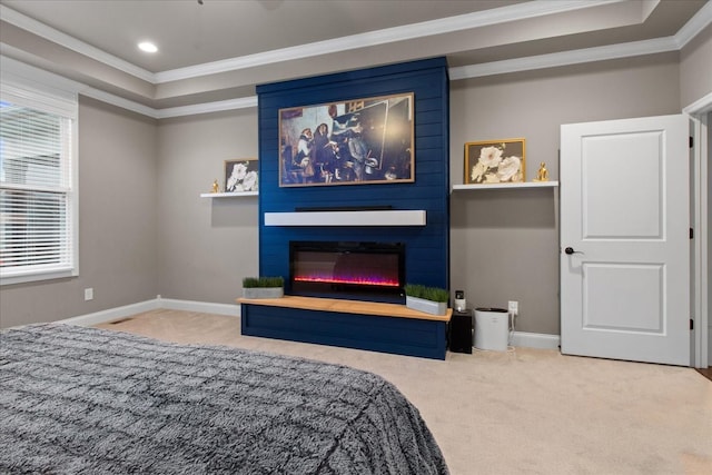 carpeted bedroom featuring a tray ceiling, crown molding, and a large fireplace