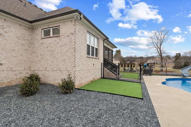 view of side of home featuring a fenced in pool, a patio, and a sunroom