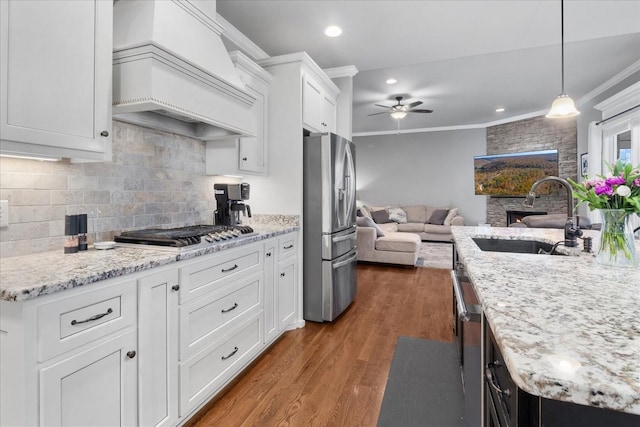 kitchen with sink, custom exhaust hood, white cabinetry, pendant lighting, and stainless steel appliances