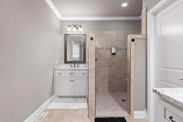 bathroom with vanity, ornamental molding, and a tile shower