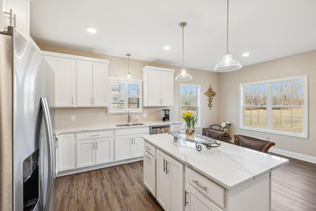 kitchen with sink, appliances with stainless steel finishes, hanging light fixtures, white cabinets, and a kitchen island