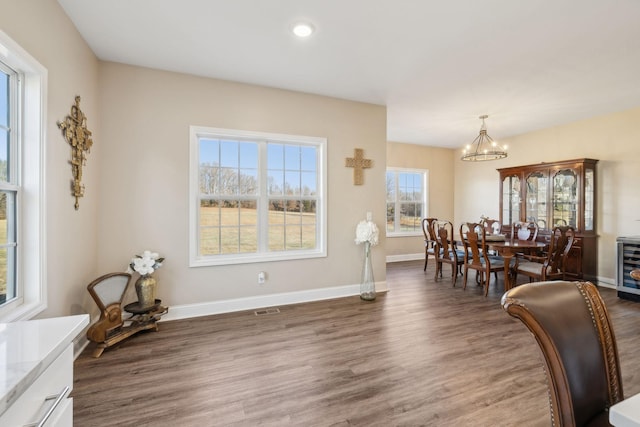 dining area with dark wood-type flooring and an inviting chandelier