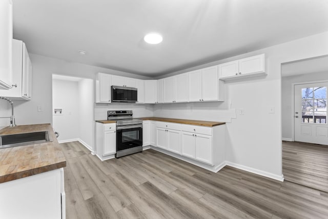 kitchen with sink, butcher block countertops, tasteful backsplash, appliances with stainless steel finishes, and white cabinets