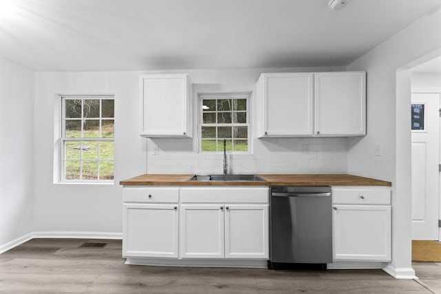 kitchen with sink, white cabinetry, wooden counters, stainless steel dishwasher, and decorative backsplash