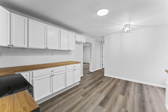 kitchen with white cabinetry, wood-type flooring, butcher block counters, and decorative backsplash