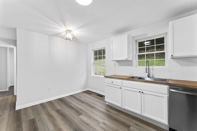 kitchen with sink, tasteful backsplash, white cabinets, wood counters, and stainless steel dishwasher