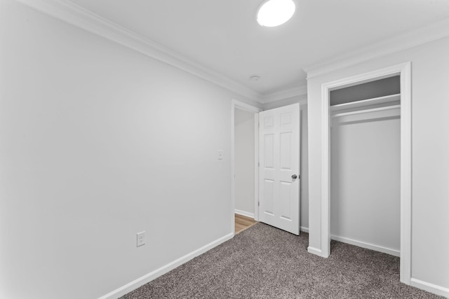 unfurnished bedroom featuring dark colored carpet, crown molding, and a closet