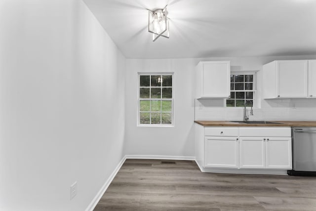 kitchen with sink, light hardwood / wood-style flooring, dishwasher, white cabinetry, and backsplash