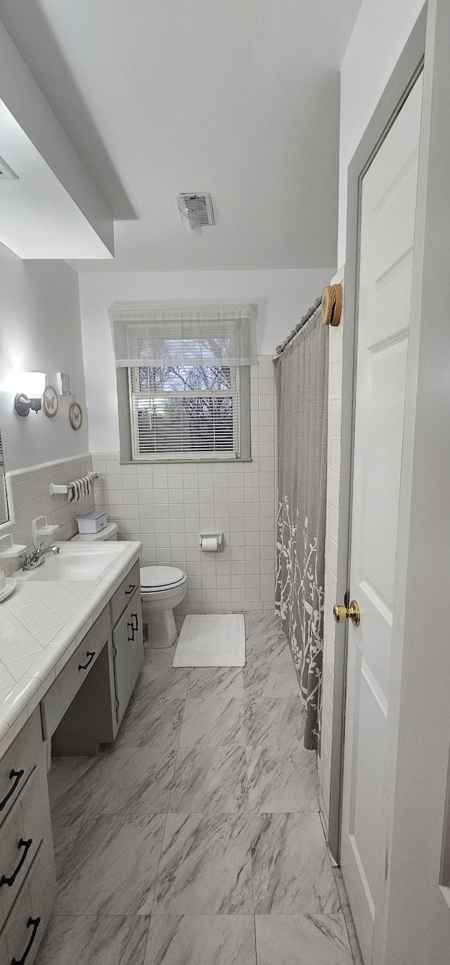 bathroom featuring tile walls, vanity, curtained shower, and toilet