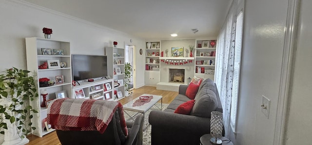 living room with crown molding, built in features, and light wood-type flooring