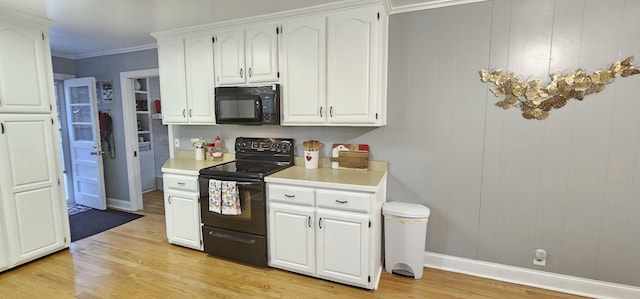 kitchen featuring white cabinetry, light wood-type flooring, crown molding, and black appliances