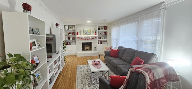 living room featuring hardwood / wood-style flooring, ornamental molding, a fireplace, and built in shelves