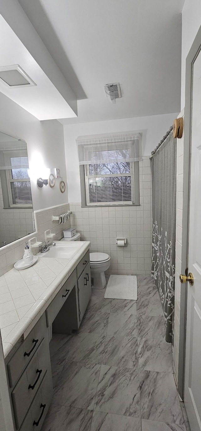 bathroom featuring tile walls, vanity, toilet, and a shower with shower curtain