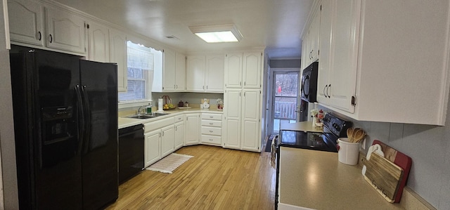 kitchen featuring white cabinetry, sink, light hardwood / wood-style flooring, and black appliances