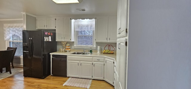 kitchen featuring sink, white cabinets, ornamental molding, light hardwood / wood-style floors, and black appliances