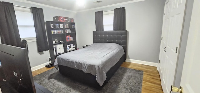 bedroom featuring multiple windows, crown molding, hardwood / wood-style floors, and a closet