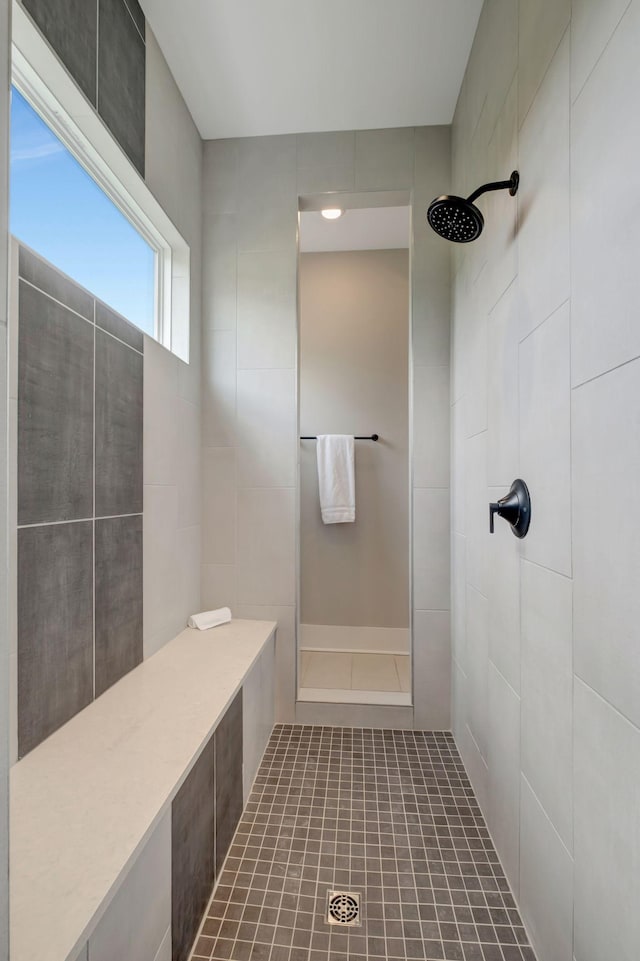 bathroom with a tile shower and tile patterned flooring