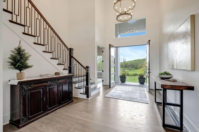 foyer featuring a high ceiling, an inviting chandelier, and light wood-type flooring