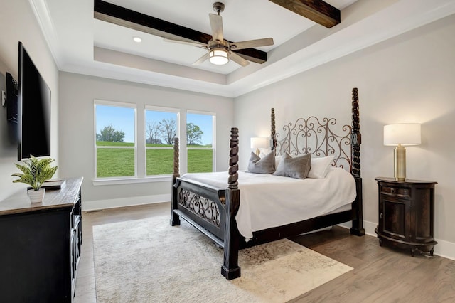 bedroom with beamed ceiling, wood-type flooring, ceiling fan, and a tray ceiling