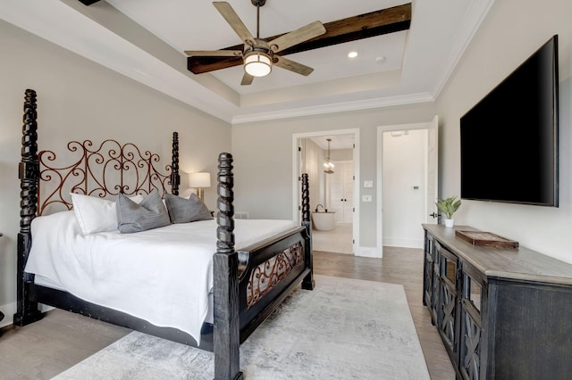 bedroom featuring hardwood / wood-style flooring, ceiling fan, ensuite bathroom, and a raised ceiling