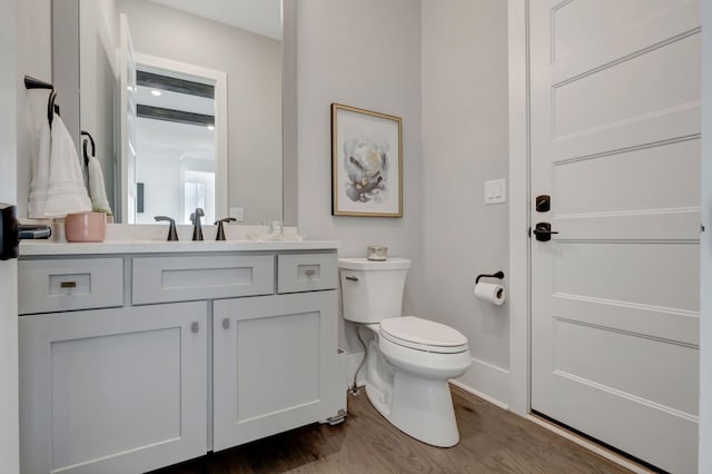 bathroom with hardwood / wood-style flooring, vanity, and toilet