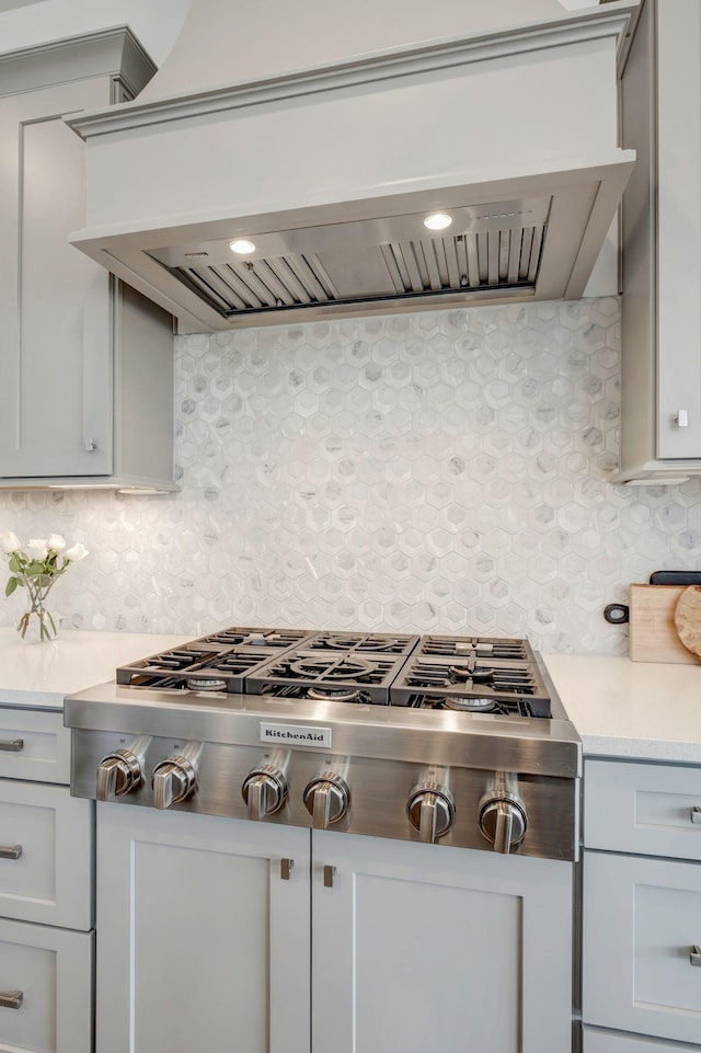 kitchen featuring stainless steel gas stovetop, premium range hood, and decorative backsplash