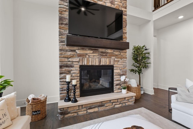 living room with a stone fireplace and dark hardwood / wood-style flooring