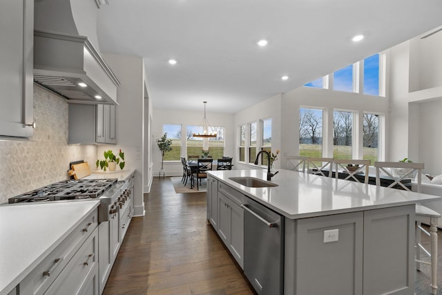 kitchen featuring appliances with stainless steel finishes, sink, a kitchen bar, custom exhaust hood, and a kitchen island with sink