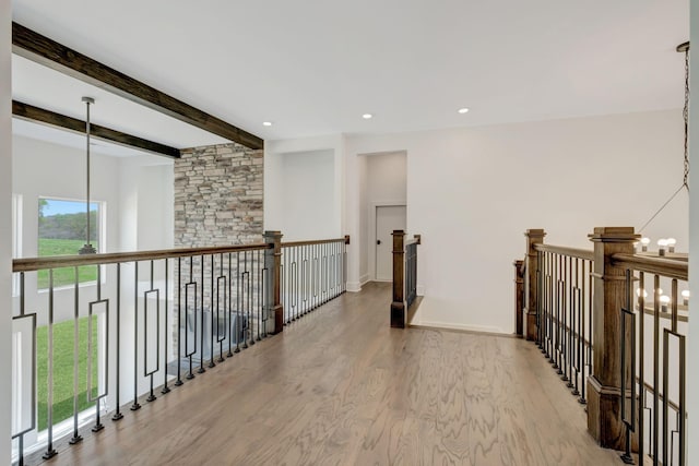 hall with a chandelier, beam ceiling, and light hardwood / wood-style flooring