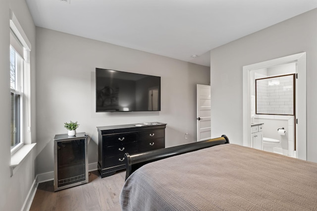 bedroom with ensuite bath and light hardwood / wood-style floors