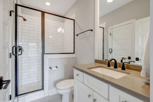 bathroom with a shower with door, vanity, tile patterned floors, and toilet