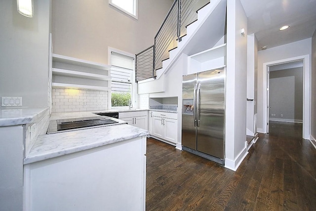 kitchen featuring dark hardwood / wood-style floors, white cabinets, light stone counters, stainless steel fridge with ice dispenser, and black electric cooktop