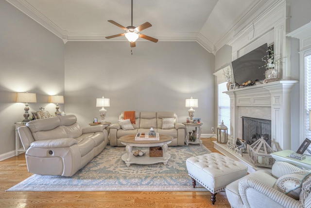 living room with crown molding, vaulted ceiling, a high end fireplace, and light hardwood / wood-style flooring