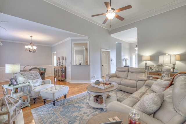 living room featuring ceiling fan with notable chandelier, ornamental molding, and light wood-type flooring