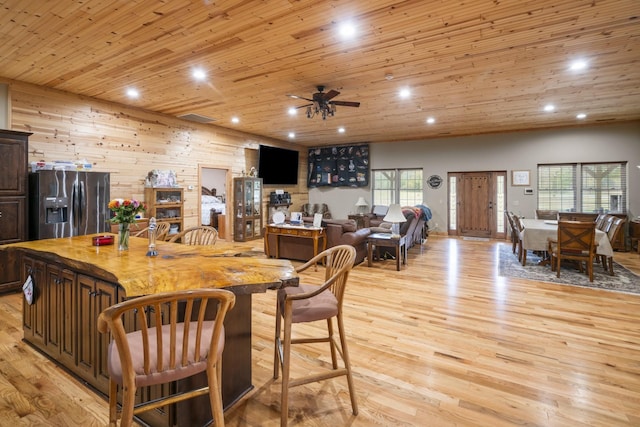 kitchen with wood ceiling, wood walls, light hardwood / wood-style floors, and stainless steel fridge with ice dispenser