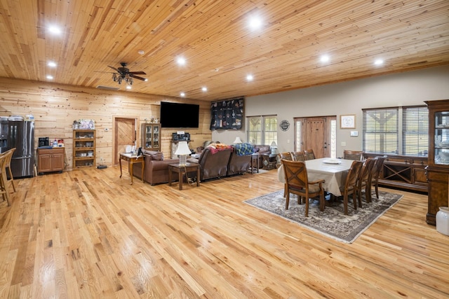 dining room with light hardwood / wood-style flooring, wooden ceiling, ceiling fan, and wood walls