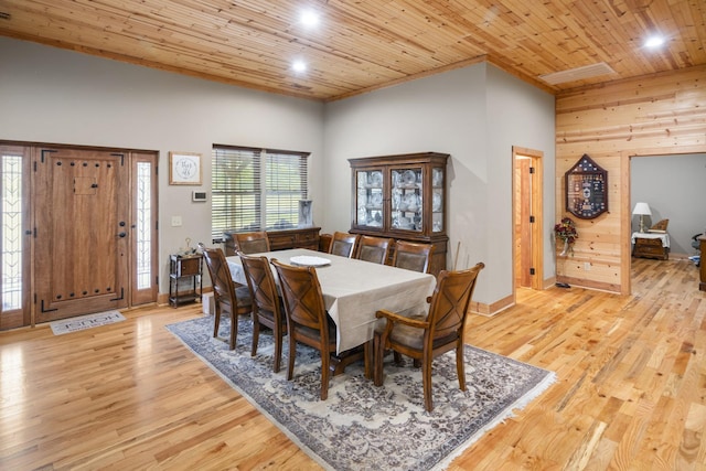 dining space with wood ceiling, light wood-type flooring, a high ceiling, and wood walls