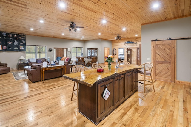 kitchen with light hardwood / wood-style flooring, a kitchen breakfast bar, a barn door, and a kitchen island