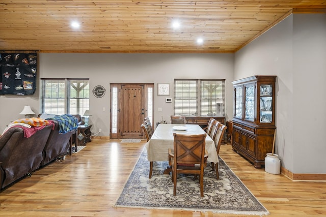 dining room with light wood-type flooring, a wealth of natural light, wood ceiling, and a towering ceiling