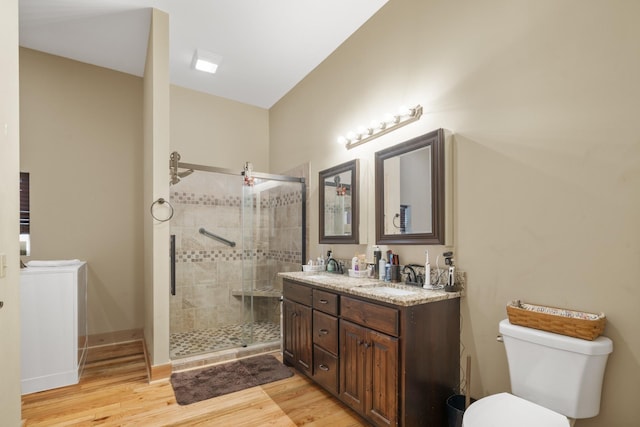 bathroom with hardwood / wood-style flooring, vanity, toilet, and a shower with shower door