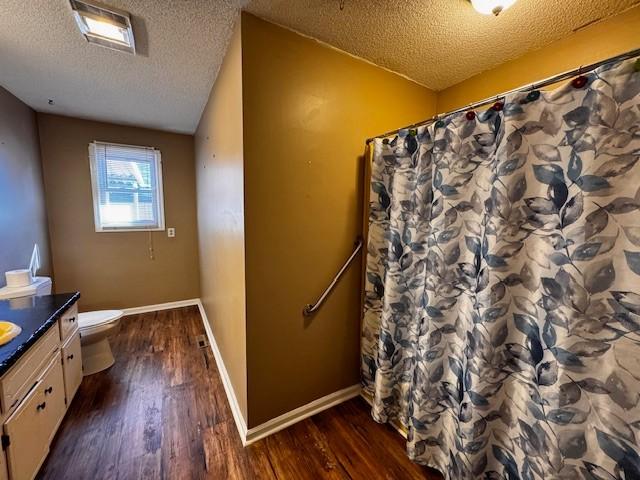 bathroom featuring hardwood / wood-style floors, vanity, toilet, a textured ceiling, and a shower with curtain