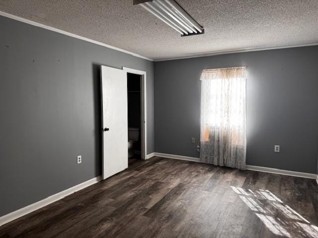 empty room with ornamental molding, dark hardwood / wood-style flooring, and a textured ceiling