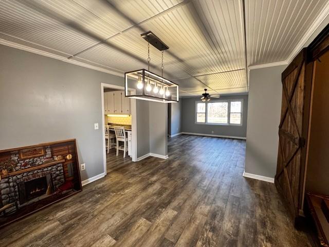 unfurnished dining area featuring dark hardwood / wood-style floors, ceiling fan, ornamental molding, and a fireplace