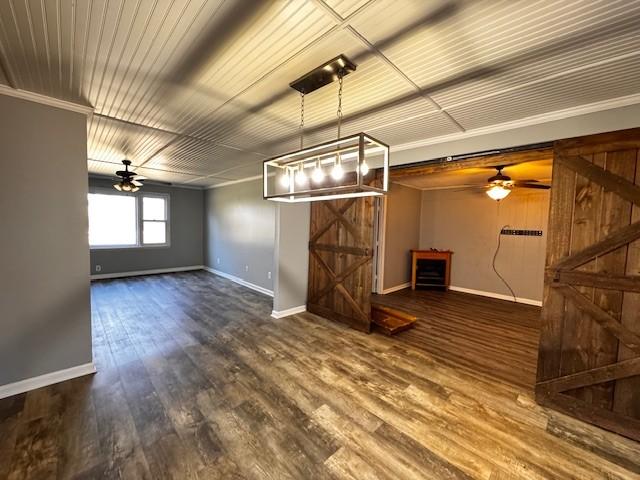 interior space featuring hardwood / wood-style flooring, ornamental molding, a barn door, and ceiling fan